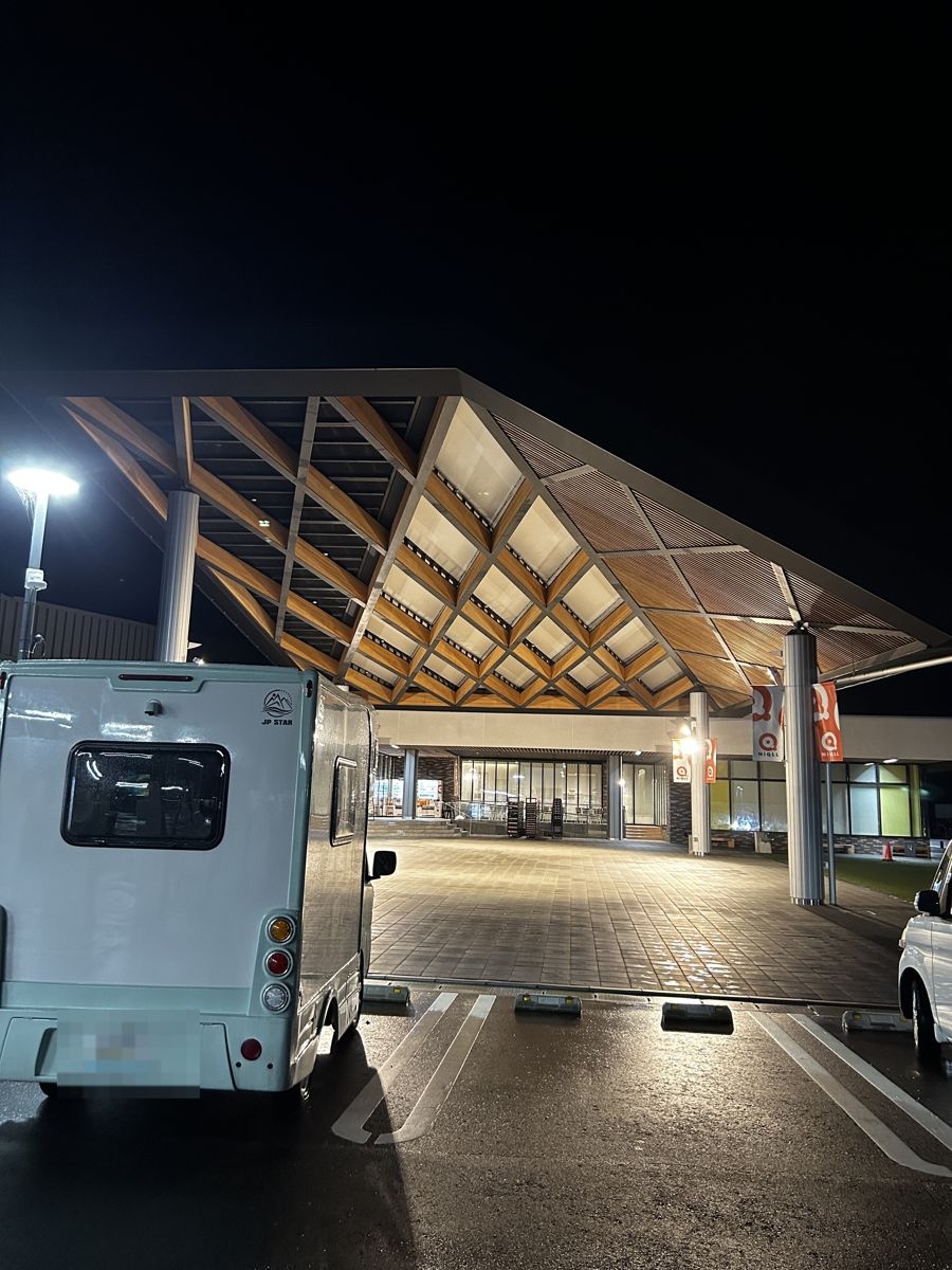 夜の道の駅NiQll都城。木の屋根の建物の前に止めたうちの軽キャン